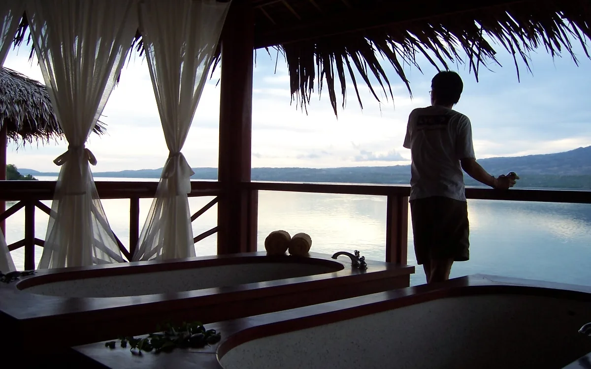 Photo: Bing Ramos / CC BY 2.0, via Wikimedia Commons A thatched spa pavilion over the water at dusk on Zaragosa Island, Badian, looking across the Tañon Strait