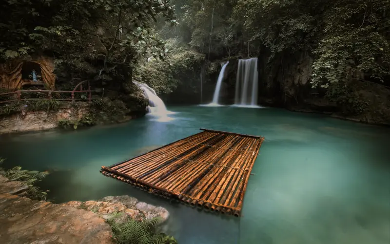 The turquoise tiered pools of Kawasan Falls in Badian, Cebu, with a bamboo raft on the water