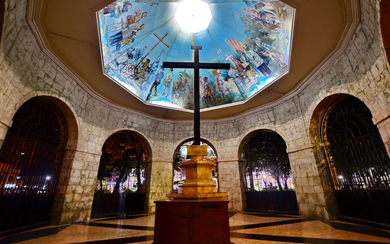 The cross inside Magellan’s Cross Pavilion in Cebu City, beside the Basilica del Santo Nino, with a mural of the 1521 baptism overhead