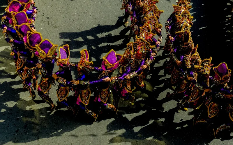 Sinulog Festival dancers in bright purple and gold costume parading through Cebu City