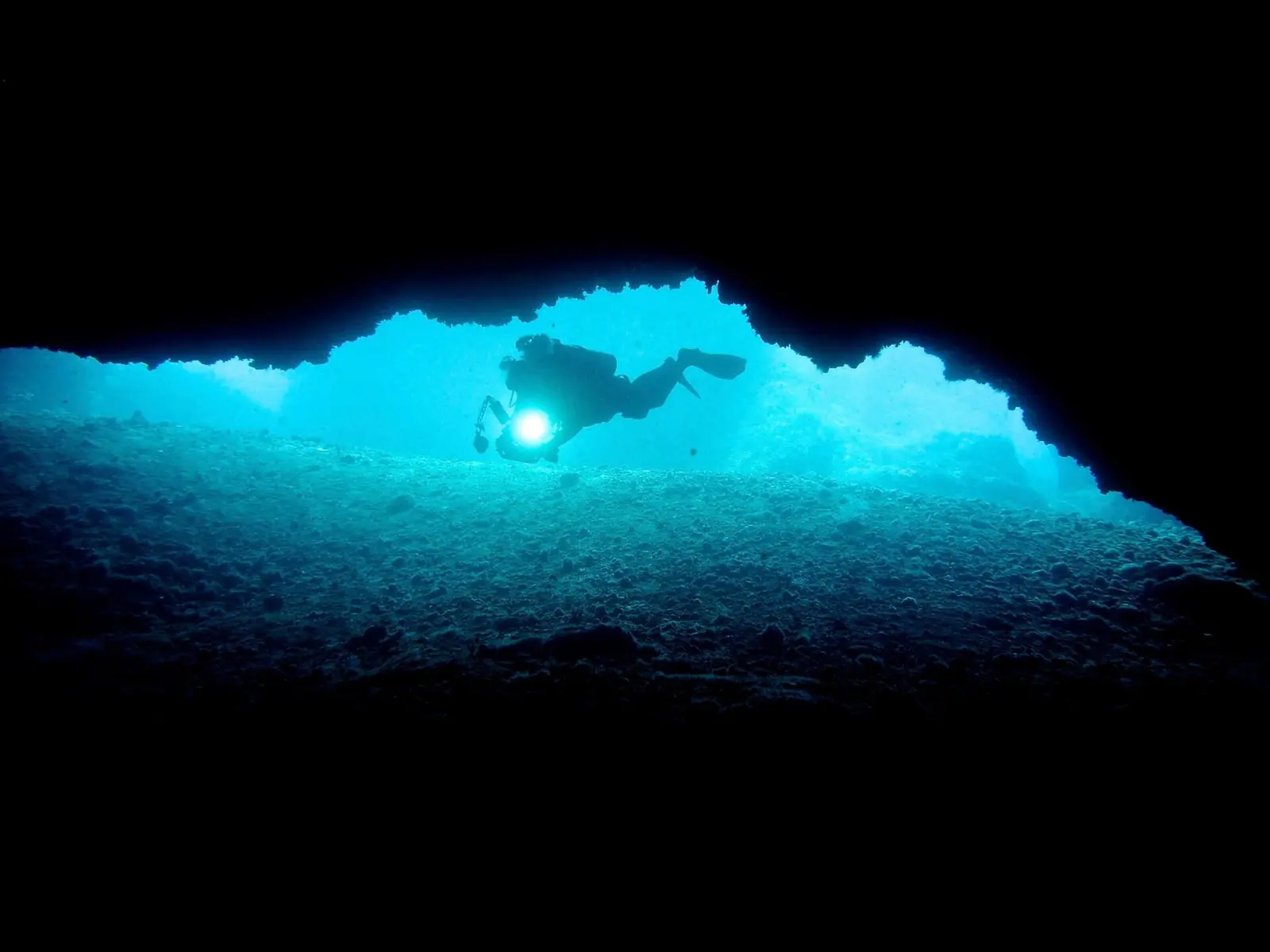 A diver silhouetted in the tunnel through Gato Island