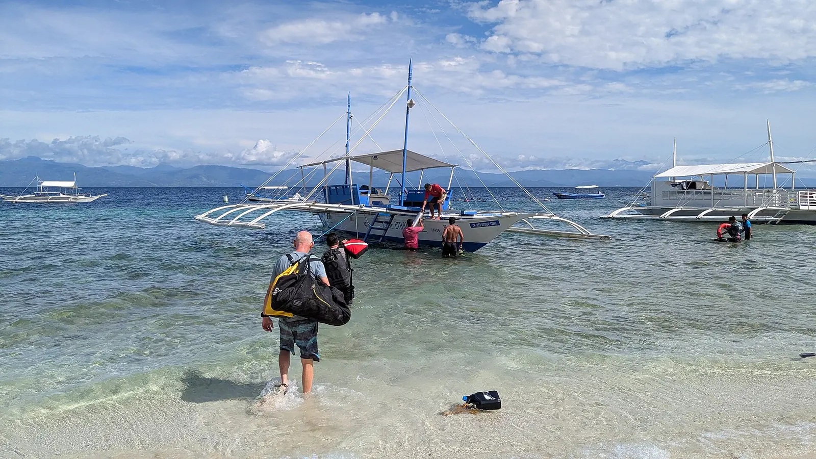 Photo: Martin Michlmayr / CC BY-SA 4.0, via Wikimedia Commons A diver wading out with gear to a dive bangka at Moalboal