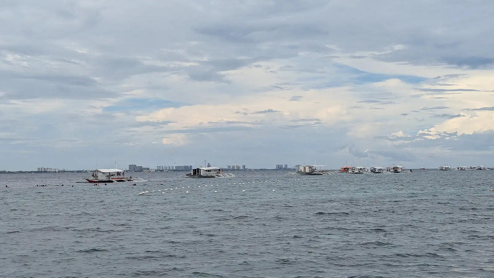 Dive and island-hopping bangkas at sea on the way to Nalusuan, with Mactan behind