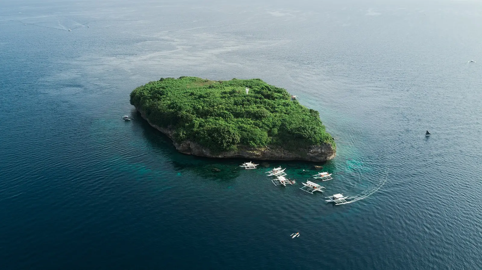 Photo: Ken Suarez kensuarez / CC0, via Wikimedia Commons Aerial view of Pescador Island off Moalboal with bangka boats moored around it