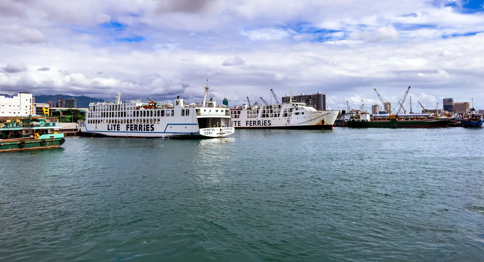 Lite Ferries inter-island ships docked at the Cebu City port with the city skyline and mountains behind